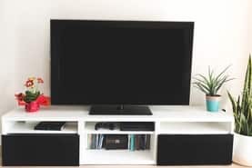This is a picture of a flat screen TV on a living room stand with two small flower pots next to it.
